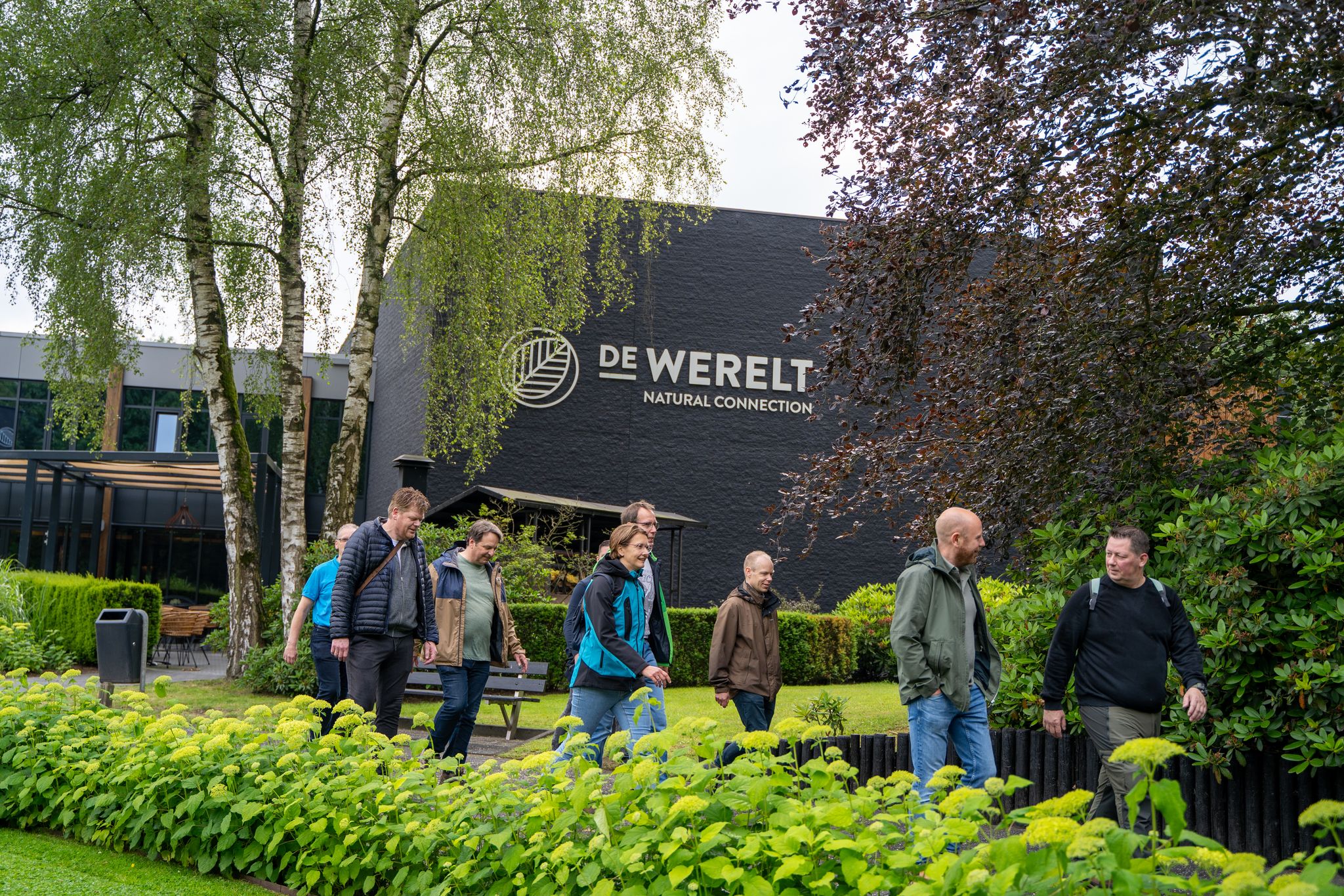 Zakelijke groep wandelt door de tuin van De Werelt Lunteren tijdens een event in het groen